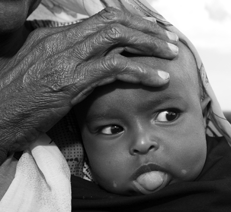 Portrait Personality 1st Place - Sgt. Alex Kleinsmith: A grandmother holds her grandson while watching Marines from 3rd Low Altitde Air Defense Battalion during a civil affairs mission to Chebellier, a village in the outskirts of Djibouti City, Africa.