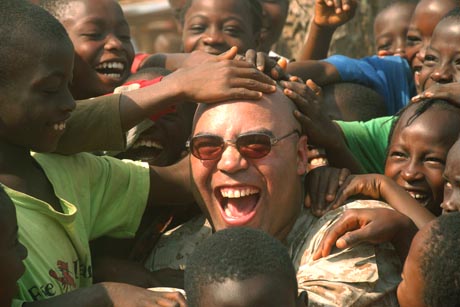 1st Place Stand Alone Photograph by Sgt. Rocco DeFilippis: Maj. Jason P. Smith, convoy commander and amphibious assault officer, takes time away from convoy operations to interact and play with some Liberian children during a convoy to deliver humanitarian supplies throughout the city of Monrovia, Liberia.  