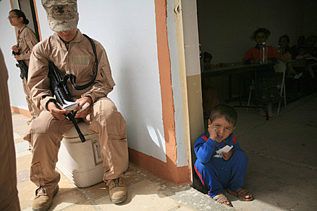 Honorable Mention Stand Alone Photograph by Cpl. Tyler Barstow: A young Kabani boy squats in the doorway to the waiting room at the Cooperative Medical Engagement as Petty Officer 2nd Class Miriam Hurtado waits for more patients, March 18. “The fact that you helped them is rewarding,” she said. “We don’t even speak the same language but you can tell they’re grateful,” said the 25-year-old who would greet and receive waves from the citizens as they left with their supplies. Hurtado said that they were happy with what they received, regardless of what it was. Whether it was lip balm or medicine, their token was a sign of the trust between the service members and them, and proof that change is being made.